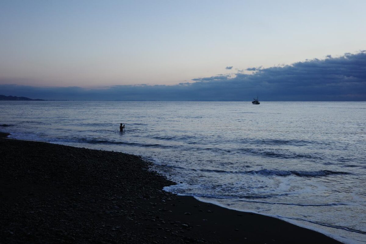 日の出時刻を迎えて禊をする男性。